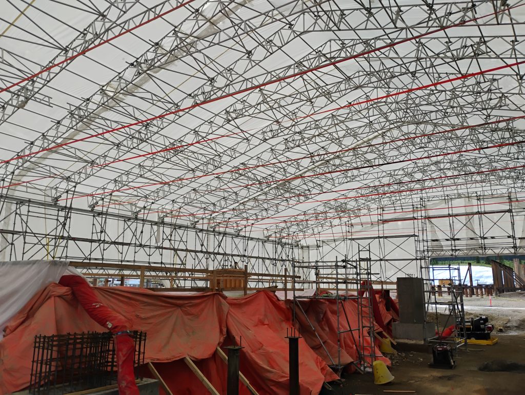 Wide-span NSP Diamond Beam aluminum roof providing weather protection for workforce housing construction; modules placed by crane.